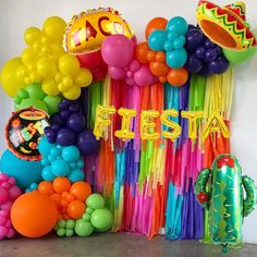 balloons, streamers and tassels are arranged on the floor in front of a wall