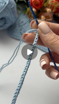 a person is knitting yarn with a blue crochet hook