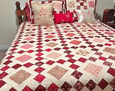 a red and white quilted bed with pillows