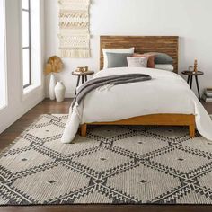 a bedroom with white walls and wooden bed frame, pillows and blankets on top of the bed