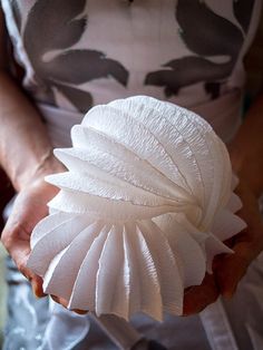 a woman is holding a white object in her hands and it appears to be made out of paper