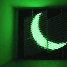 the shadow of a crescent moon is projected on a green wall