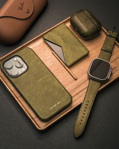 a wooden tray with an apple watch, cell phone case and other items on it