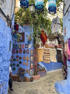 an alleyway with blue walls and hanging decorations on the wall, in morocco or india