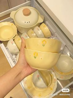 a person holding a yellow bowl in front of some dishes