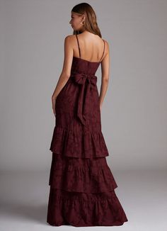 the back of a woman wearing a long dress with tiered ruffles on it