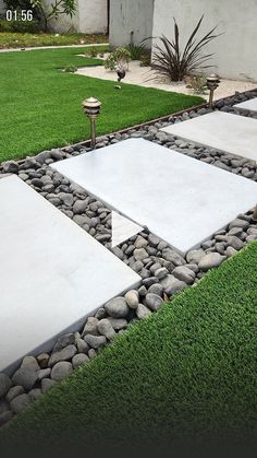 an outdoor area with grass, rocks and stepping stones