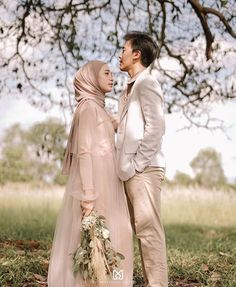 a man and woman standing next to each other under a tree