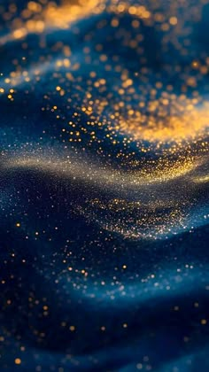 some gold glitters are on the surface of a blue and yellow background with waves