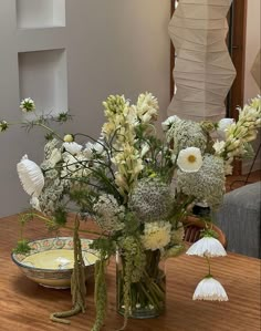 a vase filled with white flowers sitting on top of a wooden table next to a plate