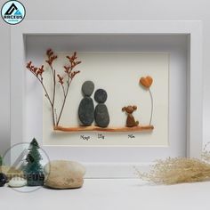 two pebbles sitting on top of a rock in a white frame