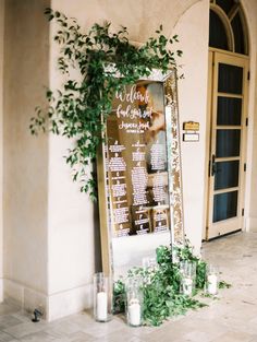 an outdoor ceremony with candles and greenery on the ground next to a large sign