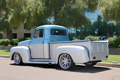 an old blue and white truck is parked on the street