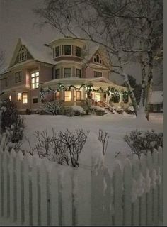 a large house is lit up at night in the snow