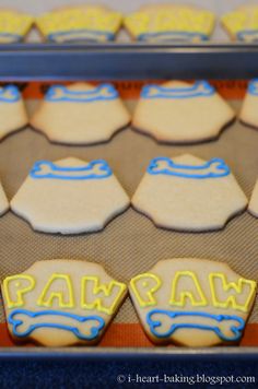 cookies with blue and yellow frosting sitting on top of a cookie sheet that says pawpaw