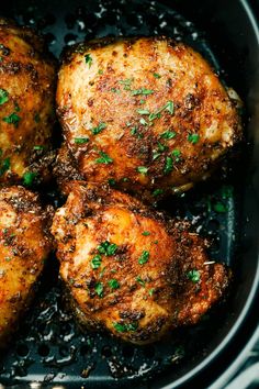 four pieces of chicken in a skillet with parsley on the top and bottom