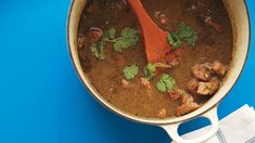 a pot filled with meat and cilantro on top of a blue table