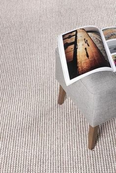 an open magazine sitting on top of a gray chair next to a white carpeted floor