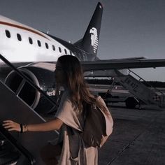 a woman is getting off an airplane at the airport