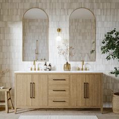 a bathroom with two sinks and mirrors on the wall next to a potted plant