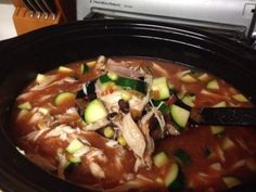 a black crock pot filled with soup and vegetables