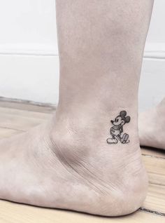 a small mickey mouse tattoo on the ankle