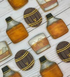 some cookies are shaped like whiskey bottles on a white wooden table with yellow and black stripes