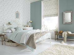 a bed room with a neatly made bed next to a window and a rug on the floor