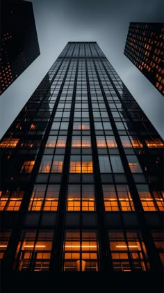 an upward view of the top of a tall building with windows lit up at night