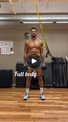 a man standing on top of a wooden floor holding a pair of dumbbells