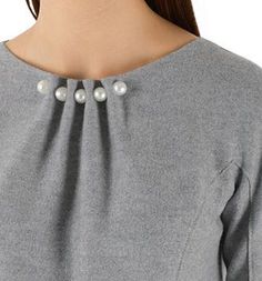 a woman wearing a gray top with pearls on it