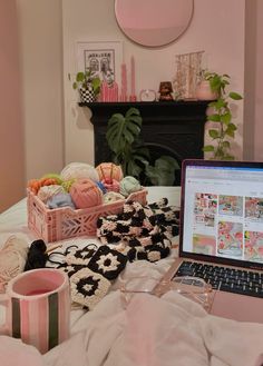 an open laptop computer sitting on top of a bed next to a cup and mug