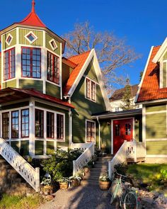 a green house with red roof and white trim on the front door, stairs leading up to the second floor