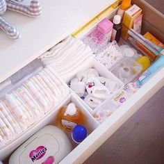 an open drawer with baby items in it and a teddy bear on the table next to it