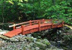 a wooden bridge over rocks in the woods