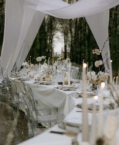 an outdoor table set up with white linens and candles for a formal dinner party