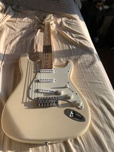 an electric guitar sitting on top of a bed