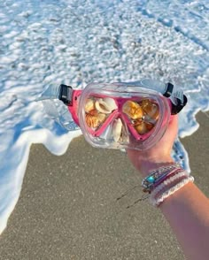 a person wearing goggles on the beach with shells in their hands and seashells inside them