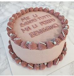 a pink cake with writing on it sitting on top of a table