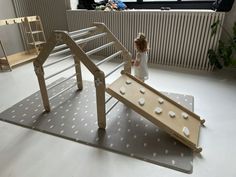 a doll standing next to a wooden structure with white dots on the floor and stairs