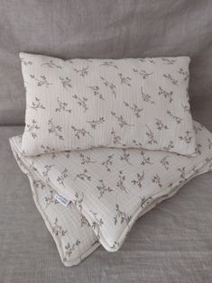 two pillows sitting on top of a couch next to each other, one with a flower pattern