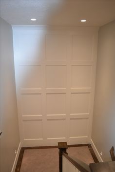 an empty room with white painted walls and carpeted stairs leading up to the door