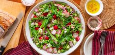 a salad with radishes and onions in a white bowl on a wooden table