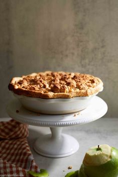 an apple pie sitting on top of a white cake plate