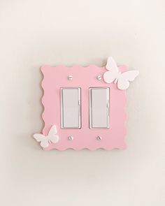 a pink light switch cover with butterflies on the wall and in the background is a white wall