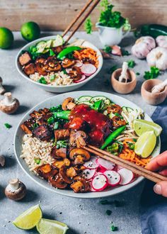 someone holding chopsticks over a plate of food with mushrooms, rice and vegetables