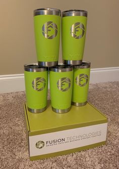 four green tumblers sitting on top of a cardboard box