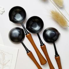 four wooden spoons are lined up next to each other on a white table top