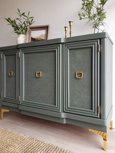 a green cabinet with gold handles and brass pulls on the doors is in front of a white wall