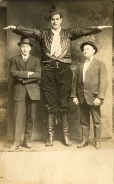 an old black and white photo of three men standing in front of a wall with their arms stretched out